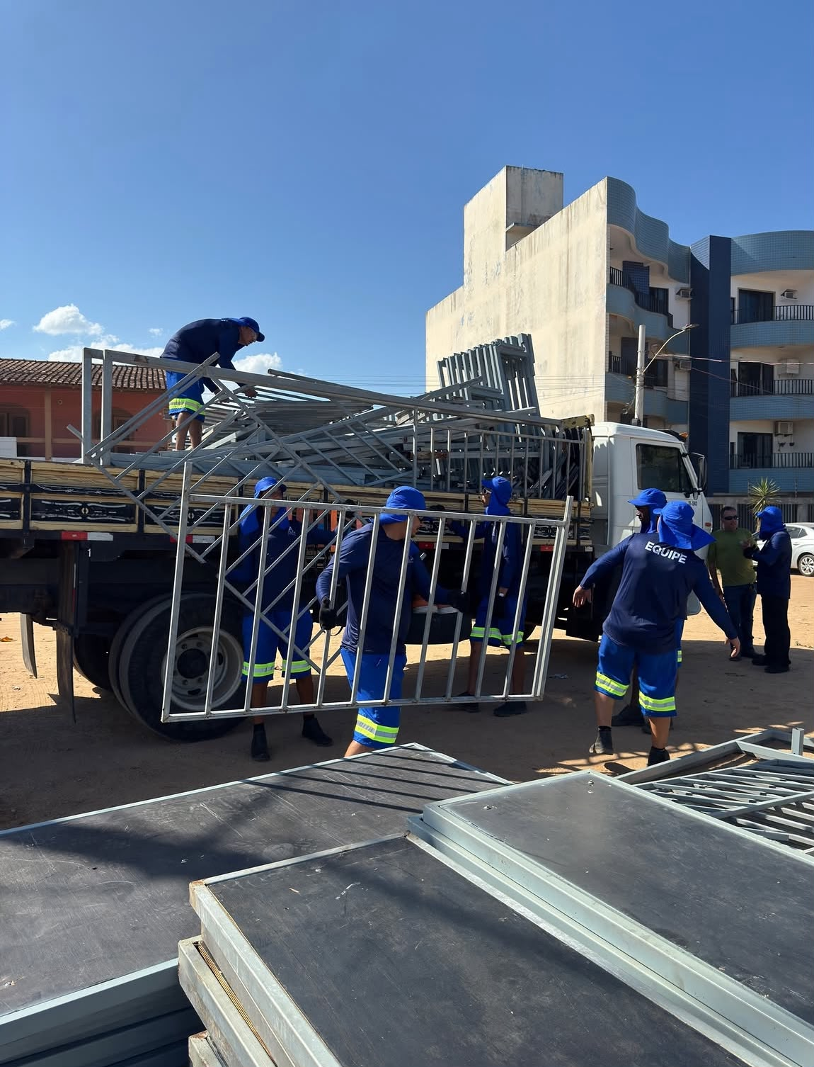 Equipe descarregando grades e estruturas metálicas para montagem de evento